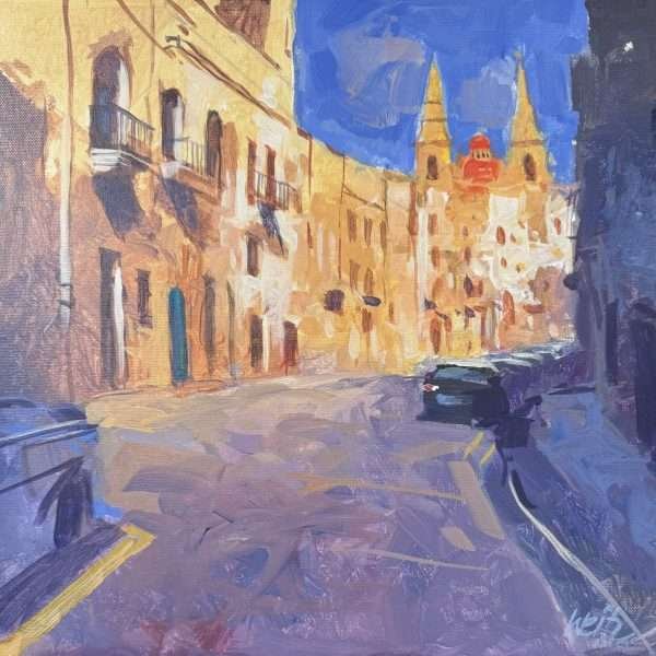 A plein air painting of a street in Mellieha by Anthony Weitz. In the bottom half of the painting is the shadowed street painted in purple whilst the top half depicts the limestone buildings leading to the church towards the right and covered in a bright blue sky.