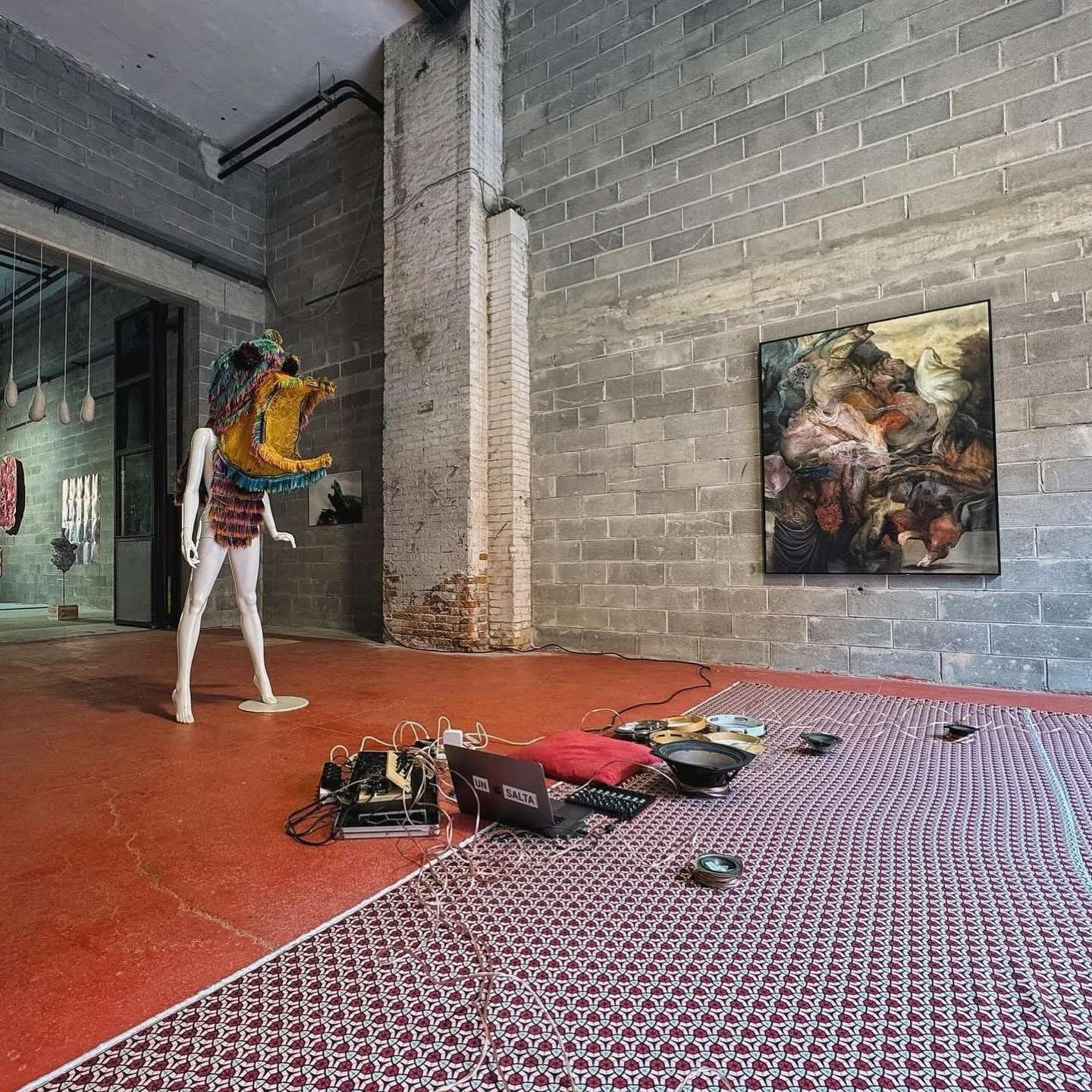 This photograph depicts the exhibition at which Mario Abela's painting was displayed at, last month in Venice. His work is visible on the right whilst to the left is a colourful, large sculpture with an installation of smaller items placed on the red painted ground, in the foreground.